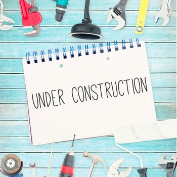 The word under construction against tools and notepad on wooden background