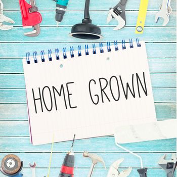 The word home grown against tools and notepad on wooden background