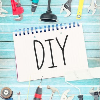 The word diy against tools and notepad on wooden background