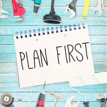 The word plan first against tools and notepad on wooden background