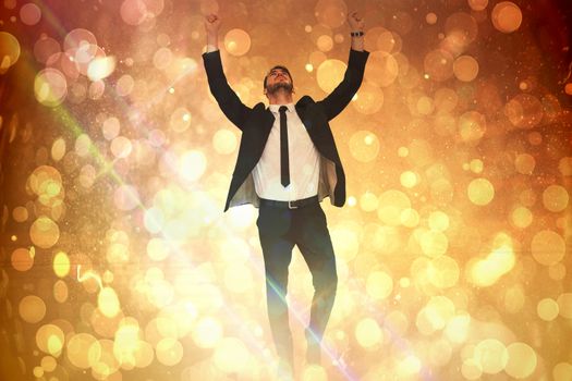 Cheerful businessman with arms up cheering  against yellow abstract light spot design