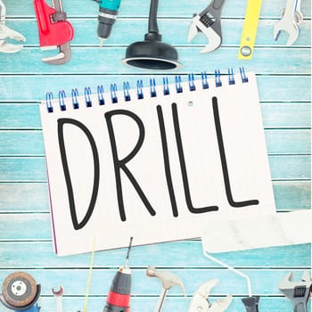 The word drill against tools and notepad on wooden background