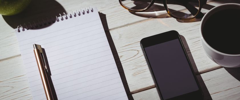 Overhead shot of notepad and smartphone on a desk