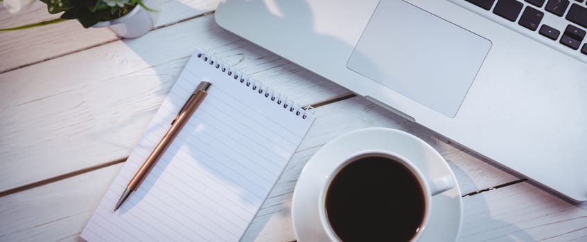 Overhead shot of laptop and notepad on a desk