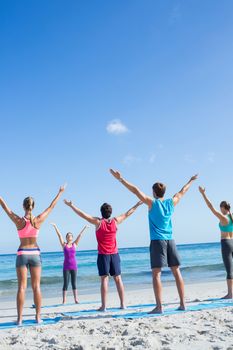 Friends stretching together with their teacher at the beach