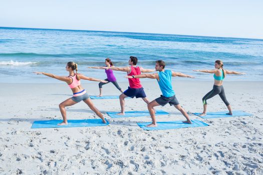 Friends doing yoga together with their teacher at the beach