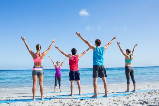 Friends stretching together with their teacher at the beach