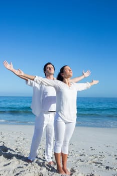 Happy couple doing yoga beside the water at the beach