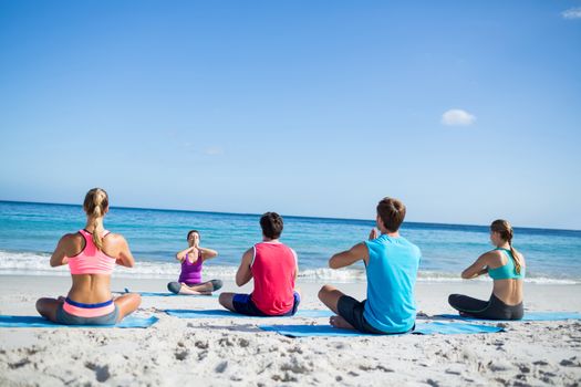 Friends doing yoga together with their teacher at the beach