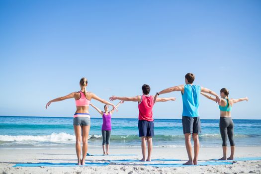 Friends doing yoga together with their teacher at the beach