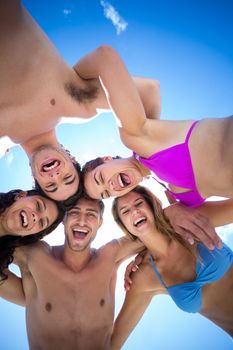 Happy friends standing in circle at the beach