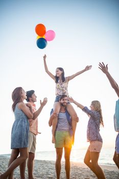 Happy friends dancing on the sand with balloon at the beach