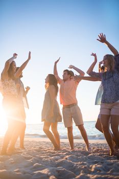 Happy friends dancing on the sand at the beach