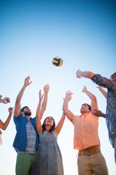 Happy friends throwing volleyball at the beach