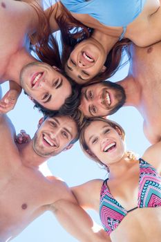 Group of friends standing in circle and smiling at camera at the beach