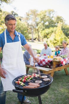 Happy man doing barbecue for his family in a sunny day