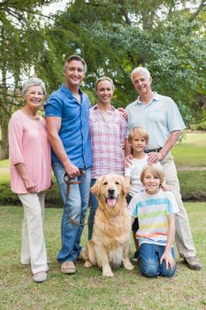 Happy family smiling at the camera with their dog on a sunny day