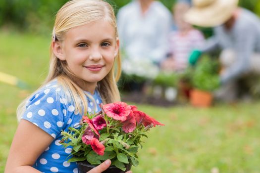 Young girl sitting with flower pot on a sunny day 