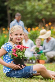 Young girl sitting with flower pot on a sunny day 