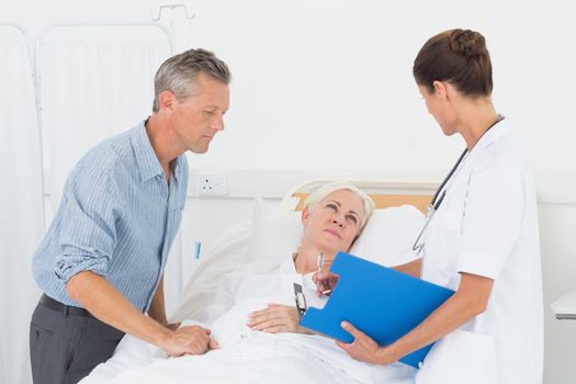 Doctor explaining report to female patient and husband in the hospital