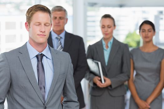 Business team meditating eyes closed in the office