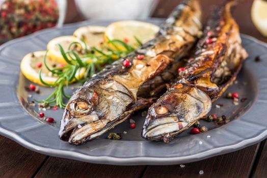 Baked Whole Mackerel Fish with Spice, Lemon and Rosemary on a Plate on Wooden Table