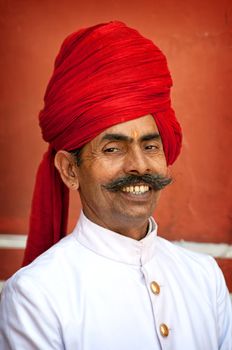 Smiling man with mustache styled as maharaja in City Palace, Jaipur, India. April 01, 2012