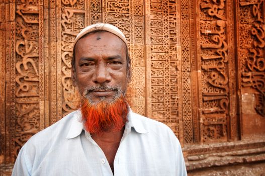 Indian man with red beard in front of Adhai-din-ka-Jhonpra ruins in a holy muslim city of Ajmer, India. April 06, 2013