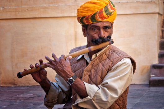 Man wearing turban playing on the flute in the Jodhpur fort, India. February 28, 2013