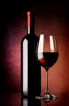 Wine in wineglass and bottle on vinous background