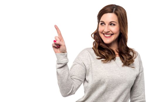 Casual woman pointing up her finger to copy space