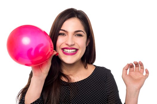 Smiling woman blowing a red balloon