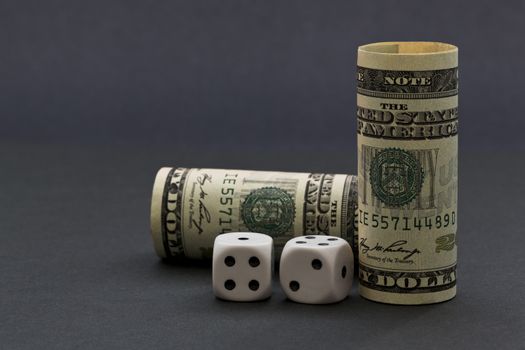 Sophisticated gray background image with United States dollars and black and white dice reflects risk in financial environment with opportunities for success. 