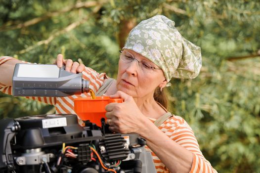 Senior woman pours oil into an outboard engine through a funnel. Breaking down the  stereotypes of women - gender and age