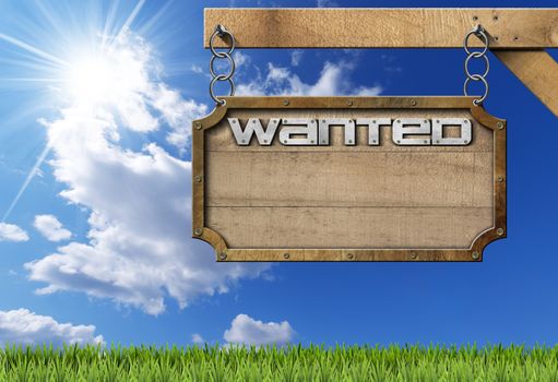 Wooden sign with planks and metal frame with text Wanted. Hanging from a metal chain on a pole on blue sky with clouds and sun rays