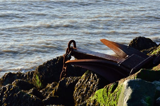 Large rusty anchor on top of group of rocks