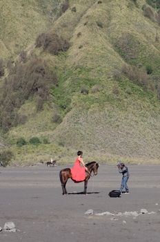 Undefined model posing on a horse under the Bromo massif. Mount Bromo is an active volcano and part of the Tengger massif, in East Java. June 28, 2014.
