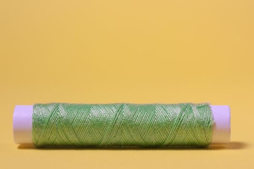 Green cotton thread on a yellow background
