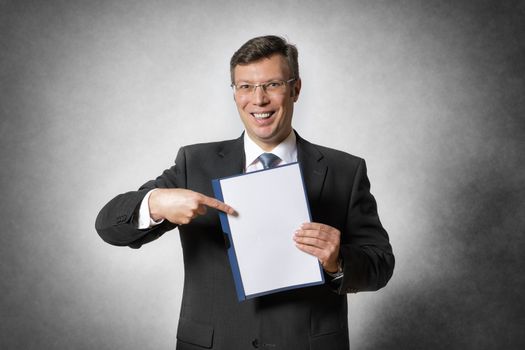 Happy businessman in dark suit holds a blank folder with free space