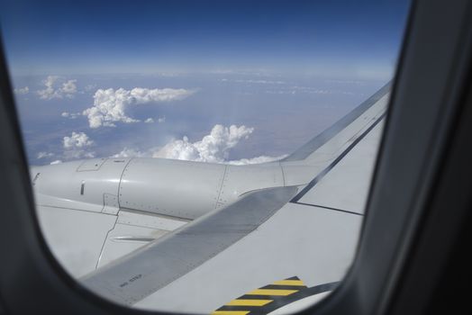 Airplane window with a view of sky and clouds.