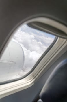 Airplane window with a view of sky and clouds.