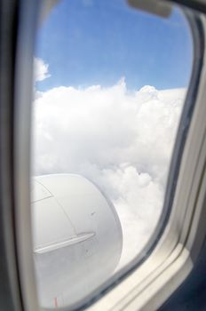 Airplane window with a view of sky and clouds.