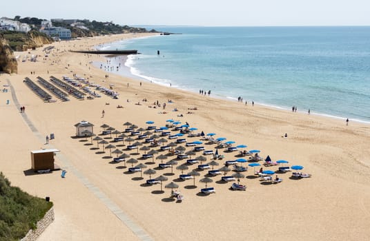 ALBUFEIRA, PORTUGAL - APRIL 23: View of crowded Falesia beach at the midday in the summer mediterranean resort Albufeira on April 23, 2015. This town is a part of famous tourist region Algarve.