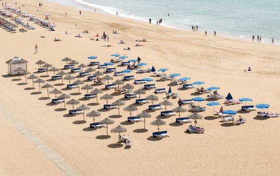 ALBUFEIRA, PORTUGAL - APRIL 23: View of crowded Falesia beach at the midday in the summer mediterranean resort Albufeira on April 23, 2015. This town is a part of famous tourist region Algarve.