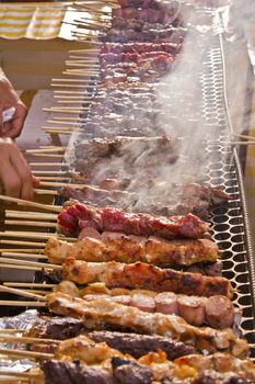 Street fair tend of skewered meat with smoke