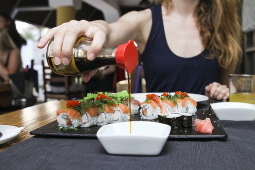 woman pour soya sauce in white  ceramic bowl