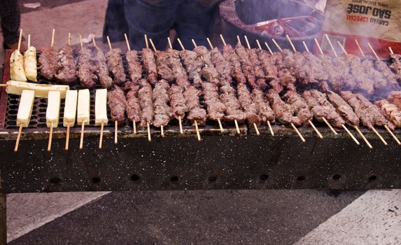 Street fair tend of skewered meat with smoke