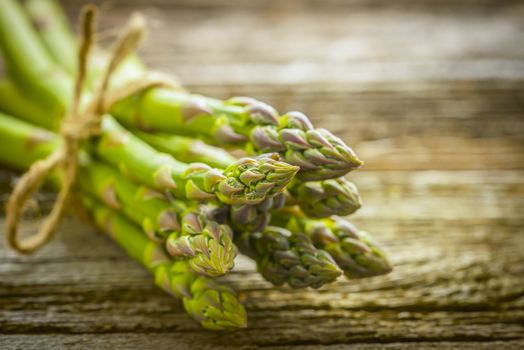 Bunch of fresh asparagus on a rustic wooden background.