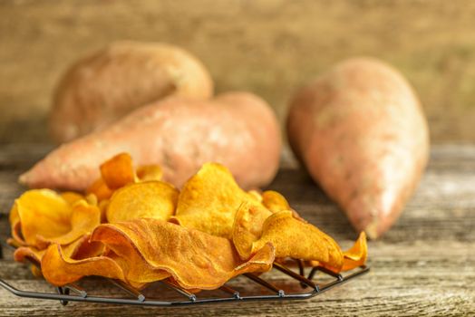 Fresh homemade sweet potato chips on a rustic background.