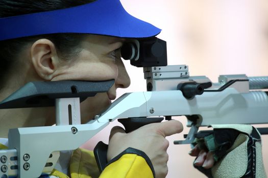 beautiful young woman aiming a pneumatic air rifle